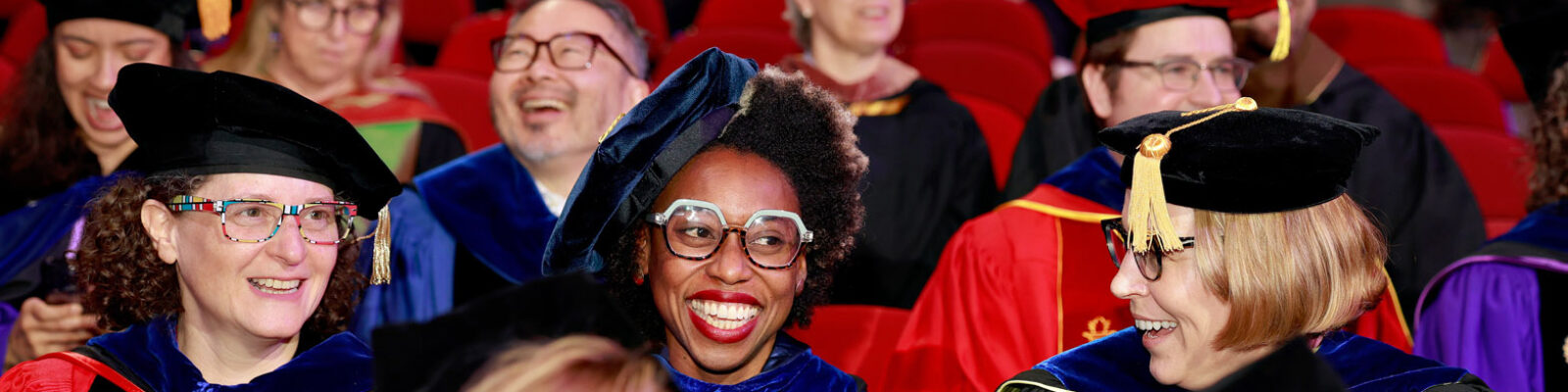 Faculty members in their regalia smiling during Commencement